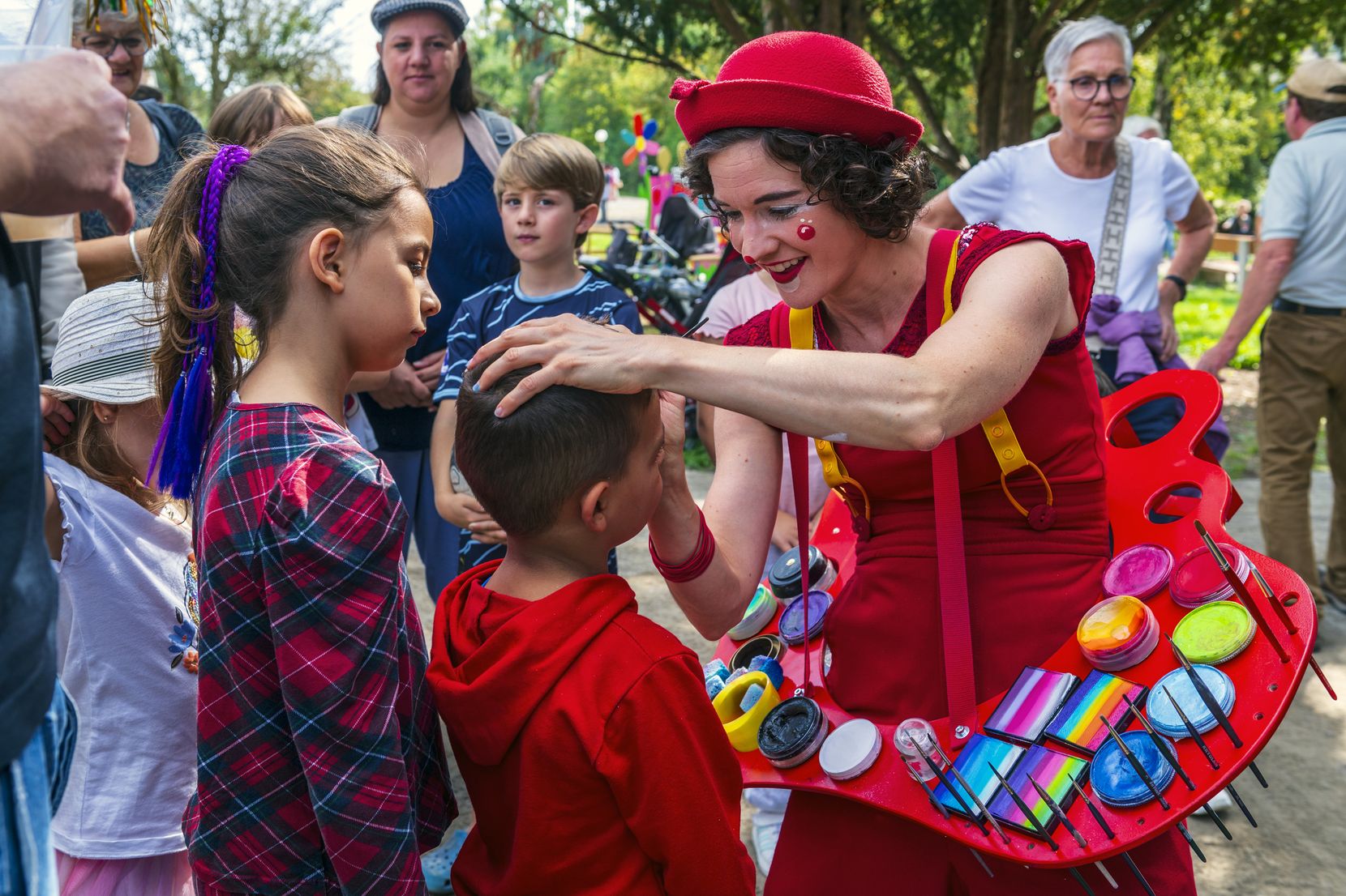Kinder werden von einer Clownin geschminkt.